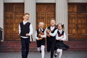 Group of kids in school uniform that is running outdoors together