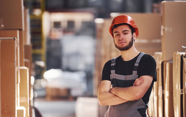 Portrait of young storage worker in warehouse in uniform and hard hat