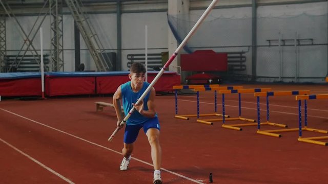 Pole vault training - a young man in blue shirt breathing in and out and starts running up before jumping