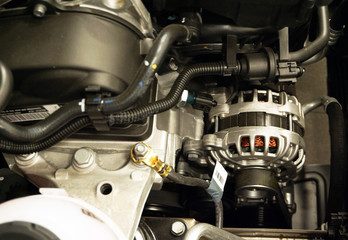 New car alternator, close-up view. An alternator installed in the engine compartment of a modern car. Diagnostics and repair of a modern car, original spare parts. Electric equipment of the car.