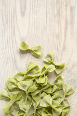 pasta with spinach in the form of bows on wooden table