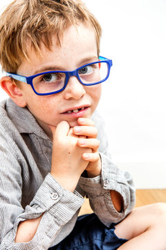 closeup portrait of serious beautiful boy with eyeglasses smiling, thinking