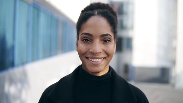 Portrait Of Beautiful Stylish African American Woman Smiling At Camera Looking Confident. Wearing Black Clothes, Urban City Background. Real People Series