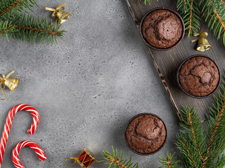 Christmas background, frame of chocolate muffins, candy cane, golden bells, fir tree branches. Layout template.