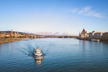  Danube river in Budapest, Hungary with floating sightseeing boat on the water. Historical center on both sides of the river. Hungarian Parliament building in the background. Budapest cityscape © ppohudka