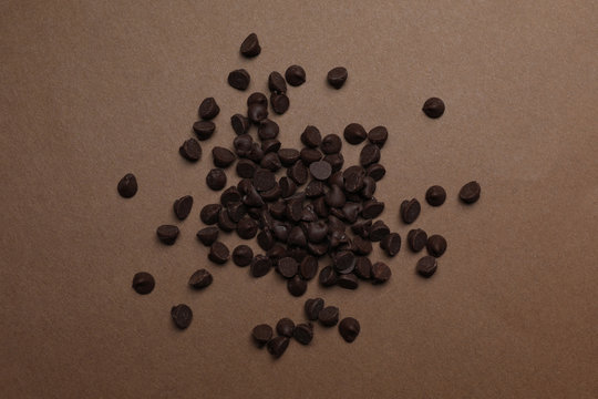Pile of delicious chocolate chips on brown background, top view