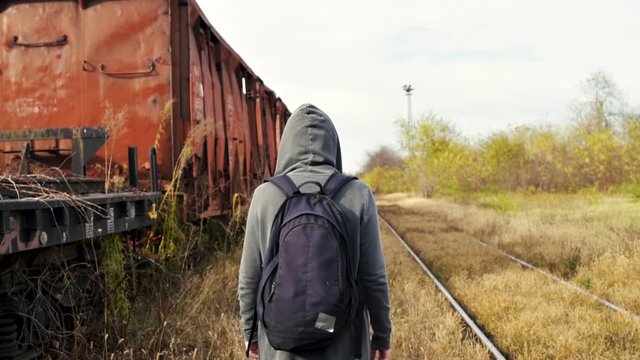 Unrecognizable homeless female person walking on rail tracks