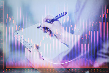 Multi exposure of hands making notes with forex chart huds. Stock market concept.