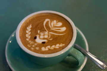 latte coffee with latte art in a coffee cup with tea spoon