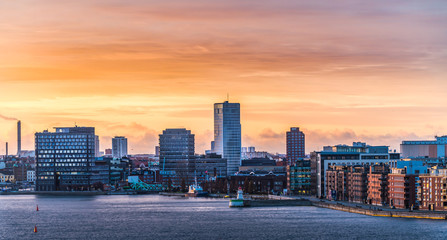 Malmo city in Sweden, with high-rise buildings and hotels close to the water with a colorful sunrise in the background