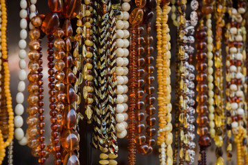 Amber background of beads and necklaces at the handicraft market. Jewelry design