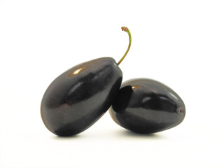 Whole fresh prunes close up. Plum fruit with shiny surface isolated on white background.