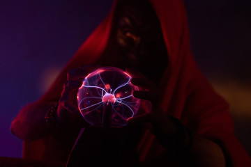 Dark creature is holding in his hands a magic globe with static electricity.