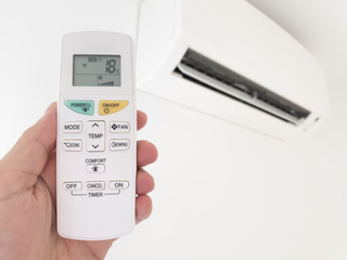 Modern airconditioner unit with a hand holding a remote.