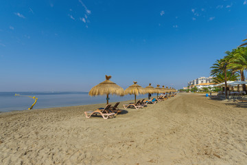Fototapeta na wymiar Umbrellas on the beach by the sea. La Manga del Mar Menor. Murcia, Spain