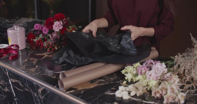 Woman florist chooses paper for a bouquet. Female hands close-up