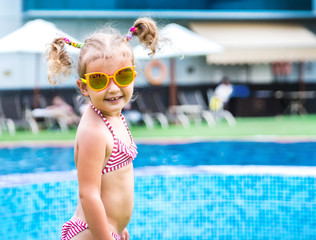 Little beautiful girl resting in the pool and learning to swim