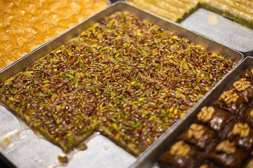 delicious street food and deserts in Istanbul city, Turkey Traditional oriental sweet pastry cookies, Turkish desert with sugar, nuts, chocolate honey and pistachio in display at a street food market