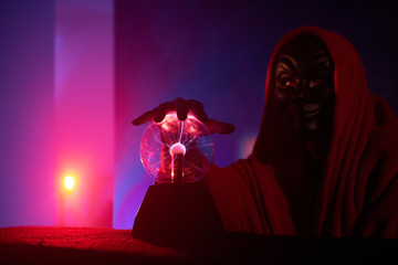 There are pink light in purple room, and bright beam of the light on the wall and wizard is sitting...