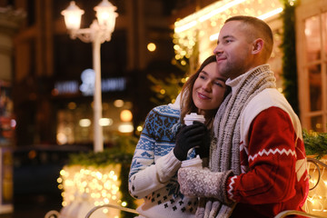 Charming couple feels happy while enjoying Christmas Eve on decorated street.