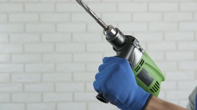 A working drill in male hands. Builder's hands with a drill.