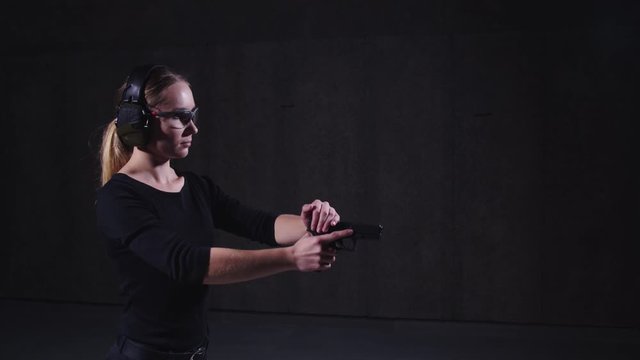 woman reloading a pistol at shooting range, getting ready to shoot the gun