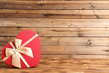 Gift box in shape of heart on brown wooden table