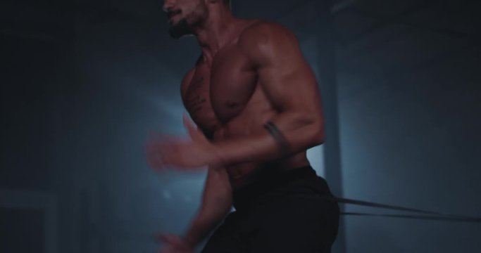 Attractive guy with strong body in a cross fitness class have a hard workout training he concentrated running while a elastic bands holding his abs