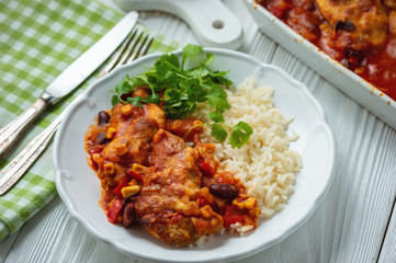 Chicken fillet baked in tomato sauce with corn and beans, served with boiled rice. Mexican style cuisine.