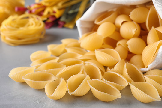 Uncooked conchiglie pasta on grey table, closeup