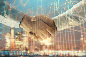 Double exposure of financial chart on cityscape background with two businessmen handshake. Concept...