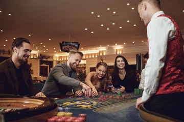 Happy people are betting in gambling at roulette poker in a casino