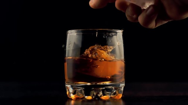 Whiskey Pouring In Glass.Cognac In Glass Floats In Slow Motion.Bourbon Or Rum Pouring In Slow Motion.Running Brandy In Glass From Bottle.Rum Flowing From Brown Bottle.