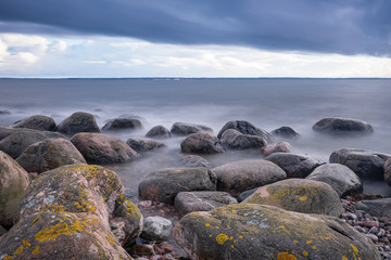 Fototapeta na wymiar Boulders, forest, shore, evening light, sunset, clouds, blue sky and rainbow on the Baltic Sea. Mohni, small island in Estonia, Europe.