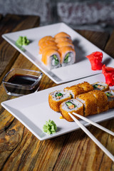 Two plates with salmon and fried roll on wood background