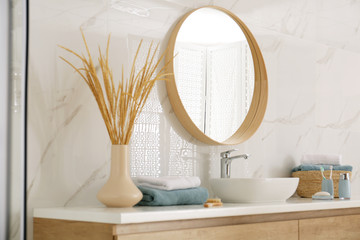 Round mirror over vessel sink in stylish bathroom