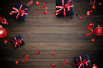 Fototapeta premium Creative frame made of Christmas fir branches, gift boxes, red decoration, sparkles and confetti on wood background. Xmas and New Year holiday, bokeh, light. Flat lay, top view