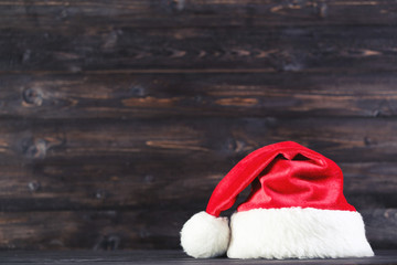 Obraz na płótnie Canvas Red santa hat on brown wooden background
