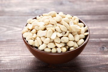 Peanuts in bowl on brown wooden table