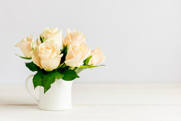 Romantic bouquet  of  pastel cream roses in a jar on a white background.
