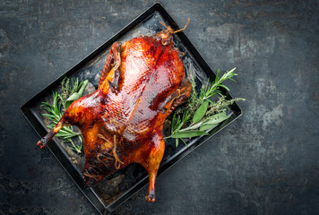 Traditional roasted stuffed Christmas Peking duck with herbs as top view on a rustic board with...