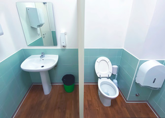 wide angle view of a toilet with the wooden floor and tiled wall