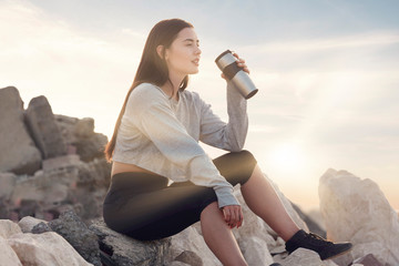 Beautiful brunette fitness model wearing a black tights and baggy gray top sitting on pile of...