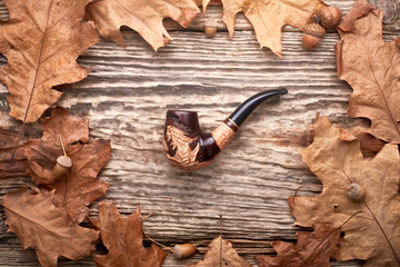 Obraz na płótnie Canvas Tobacco pipe on old autumn wooden background.