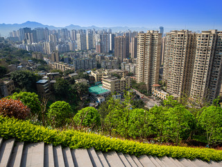 Chongqing, China - March 20, 2018:Top view of a residential quarter in the Chinese city of Chongqing, sunny day in metropolis. Park, stairs. Mountains in the distance.