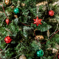 Closeup of christmas fir tree decorated with red, gold, green toys, balls and garland. Traditional winter holidays Christmas / New Year.