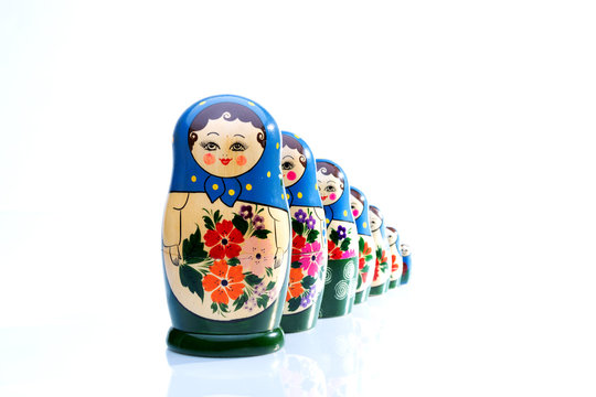 Matroschka-Familie freigestellt auf wei&szlig;em Hintergrund mit spiegelnder Oberfl&auml;che 