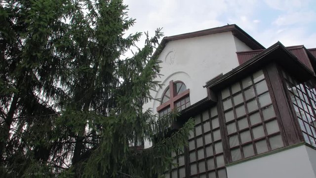 Old christian church building facade with wooden cross and spruce outdoor