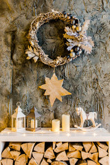 Christmas, New Year magic decor, the fireplace is decorated with candles, lamps, wreath made of rattan and twigs and a burning garland. Traditional winter holidays Christmas / New Year. 