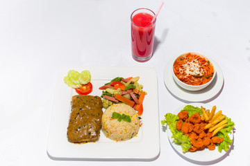 Asian style ramadan sehri food set. Healthy full course meal. A plate of calamari, plane rice and fish stake and saute vegetable and spice pasta with a glass of watermelon juice on white background.